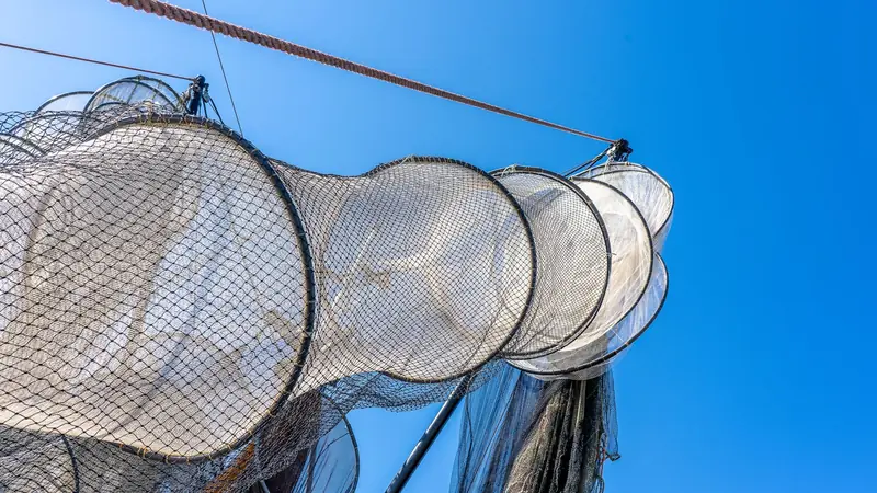 A fishing net drawn tight against the side of a boat