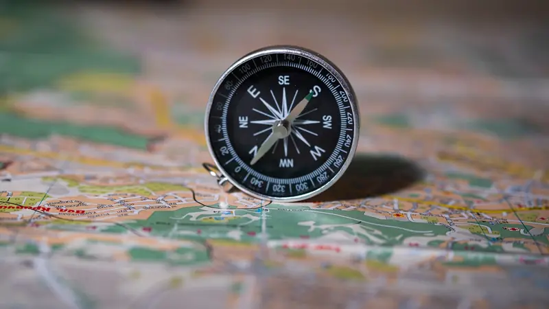 A brass compass resting on an unfolded map