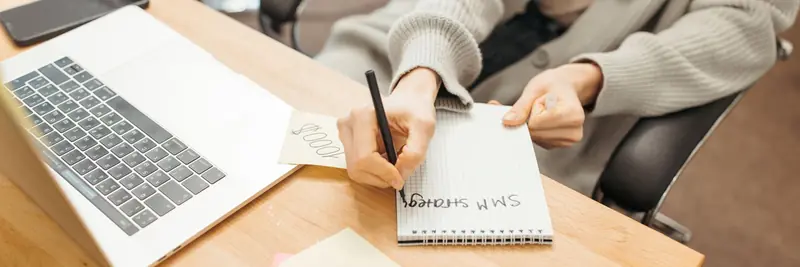 A desk with a laptop, notes and a printed content plan