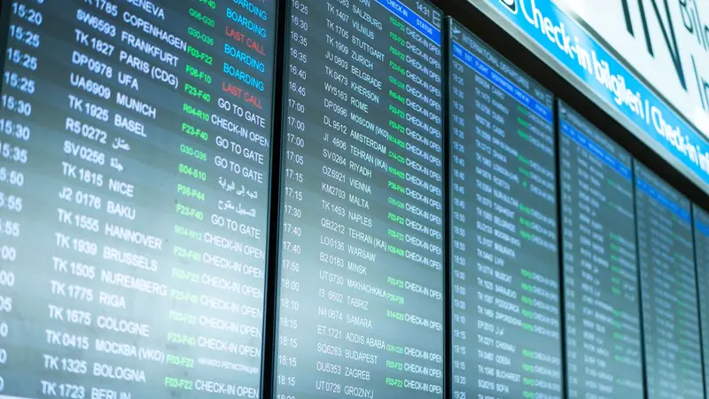 An airport departure board listing international destinations