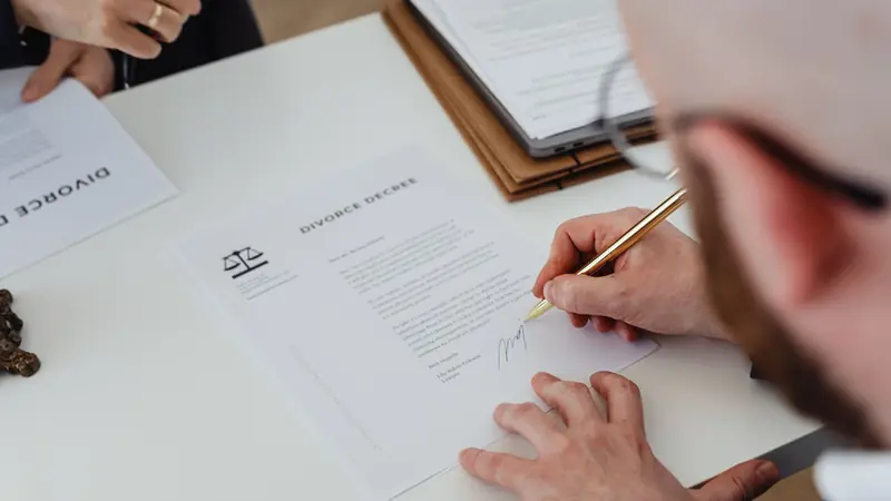 A hand signing a printed contract with a fountain pen
